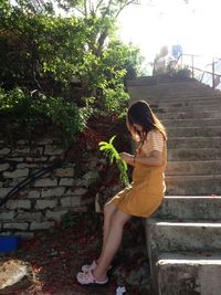Side view of woman holding umbrella against wall