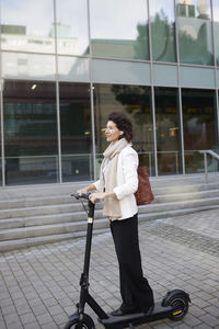 Businesswoman riding electric push scooter