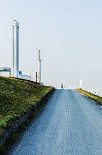 Man walking on road against clear sky