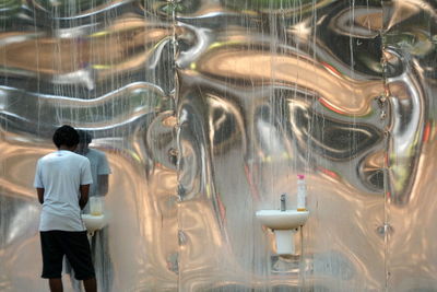 Rear view of man standing by glass window