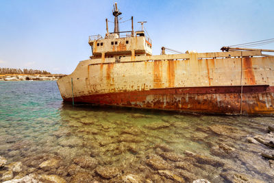 Abandoned ship in sea against sky