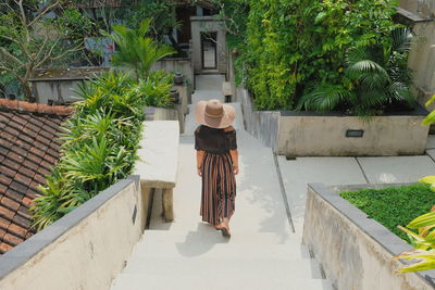 Rear view of woman standing by footpath