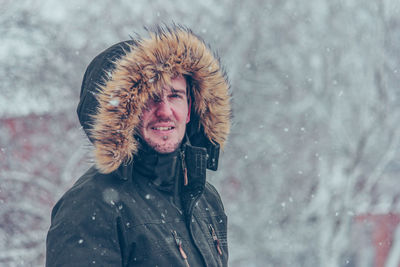 Portrait of man wearing fur coat standing outdoors during snowfall