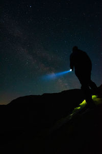 Side view of silhouette woman standing against sky at night