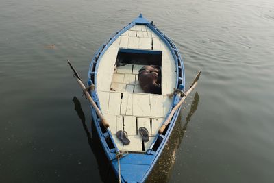 High angle view of shirtless man sleeping on boat in lake