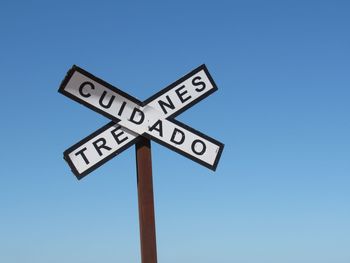 Low angle view of road sign against clear blue sky