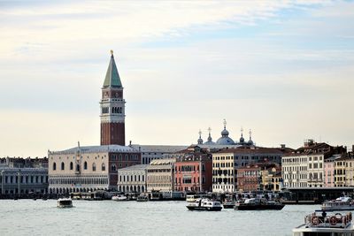 View of building by river against cloudy sky