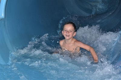 Portrait of shirtless boy enjoying in water slide