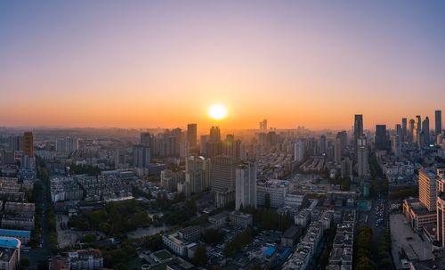 Aerial view of buildings in city against sky during sunset