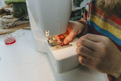 Hands of fashion designer adjusting thread in sewing machine