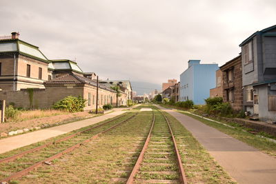 View of railroad tracks by buildings against sky