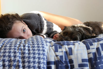 Portrait of young woman lying on sofa with dog