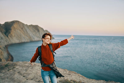 Woman standing on rock at beach against sky