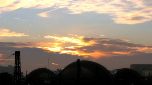 Modern city against sky during sunset