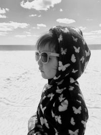 Close-up of woman wearing sunglasses on beach against sky
