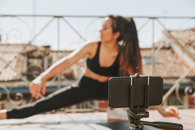 Young sporty fit woman coach doing online lessons through video call on her mobile phone