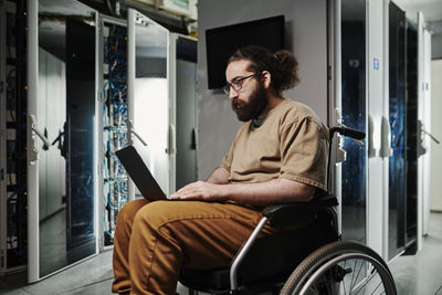 Technician with disability working on laptop in server room