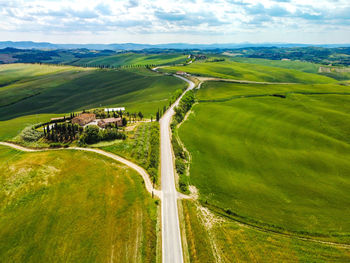 High angle view of road amidst field against sky