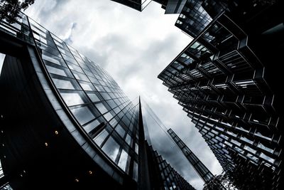 Low angle view of skyscrapers against cloudy sky