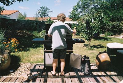 Rear view of man sitting on seat in yard