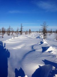 Snow covered land against blue sky