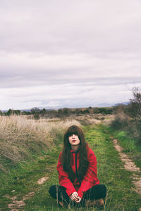 Portrait of young woman wearing sitting on grassy footpath