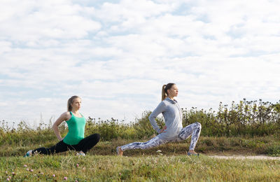 Two women exercising on grass in park