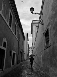 Rear view of man walking on street amidst buildings in city
