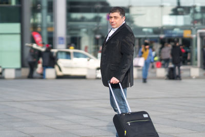 Businessman with luggage standing in city