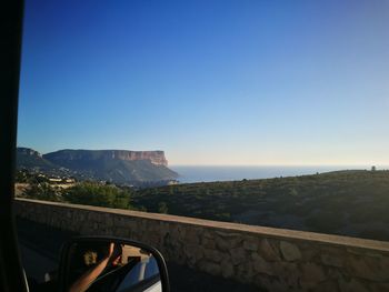 Road by sea against clear blue sky