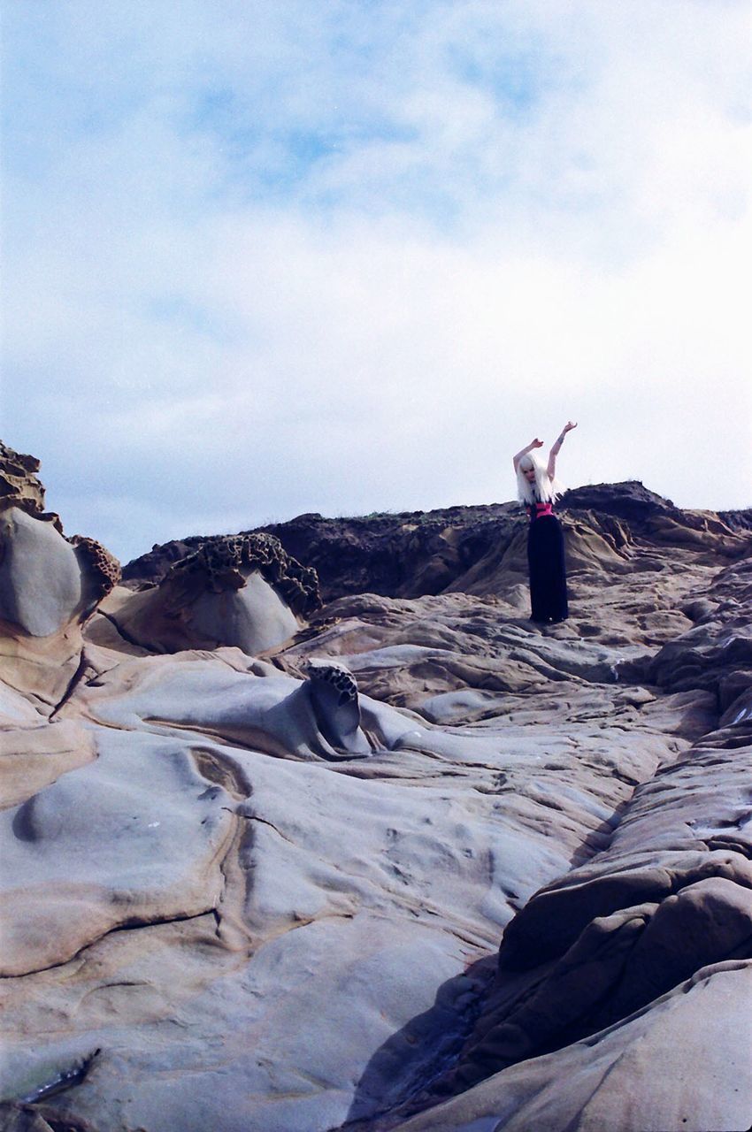 lifestyles, full length, leisure activity, sky, rock - object, young adult, standing, rock formation, casual clothing, tranquil scene, tranquility, nature, landscape, young women, cloud - sky, rock, side view, rear view