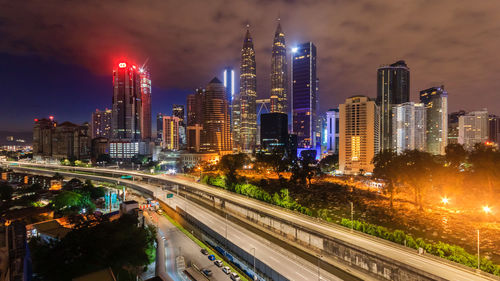 Illuminated modern buildings in city against sky at night