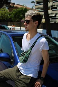 Portrait of young man sitting on car