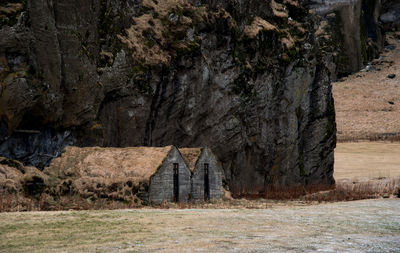 Typical turf houses used as warehouses under a rocky cliff in south iceland