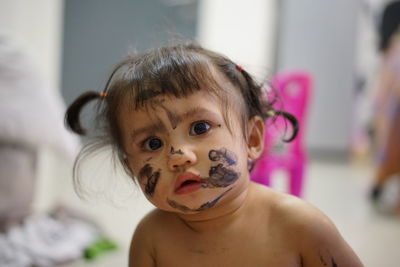 Portrait of shirtless baby with messy face paint at home