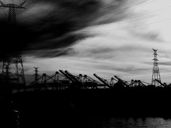 Low angle view of silhouette cranes against sky at dusk