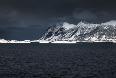 Snow covered mountain by sea against sky