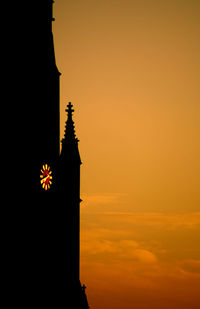 Low angle view of silhouette building against orange sky