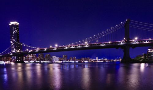 Illuminated bridge over river at night