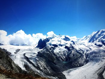 Snow covered mountains against blue sky on sunny day