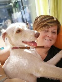 Portrait of woman with dog against wall