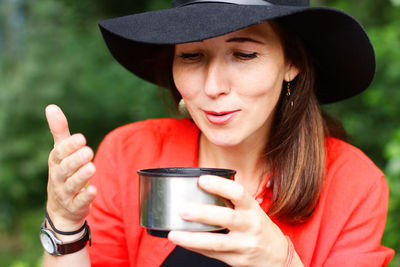 A girl blows tea from a thermos on a walk. active recreation in the form of a walk through