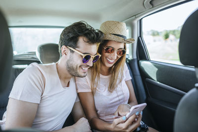 Couple in the back seat of a car looking at a cell phone