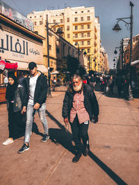 Full length of friends walking on street in city