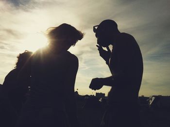 Silhouette people standing against sky during sunset