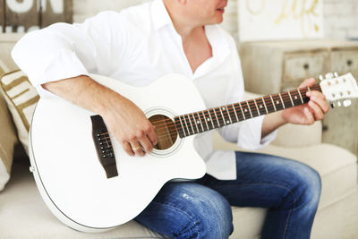 Midsection of man playing guitar