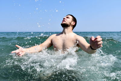 Young man in sea against sky