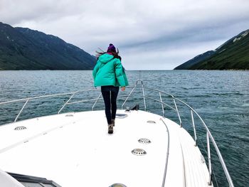 Rear view of woman standing on boat in sea against sky