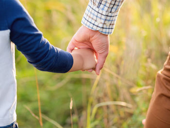 Father and son hold hands. emotional and moral support.man and boy shake hands.golden hour outdoors.