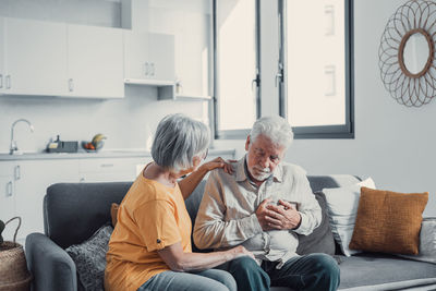 Side view of woman sitting on sofa at home